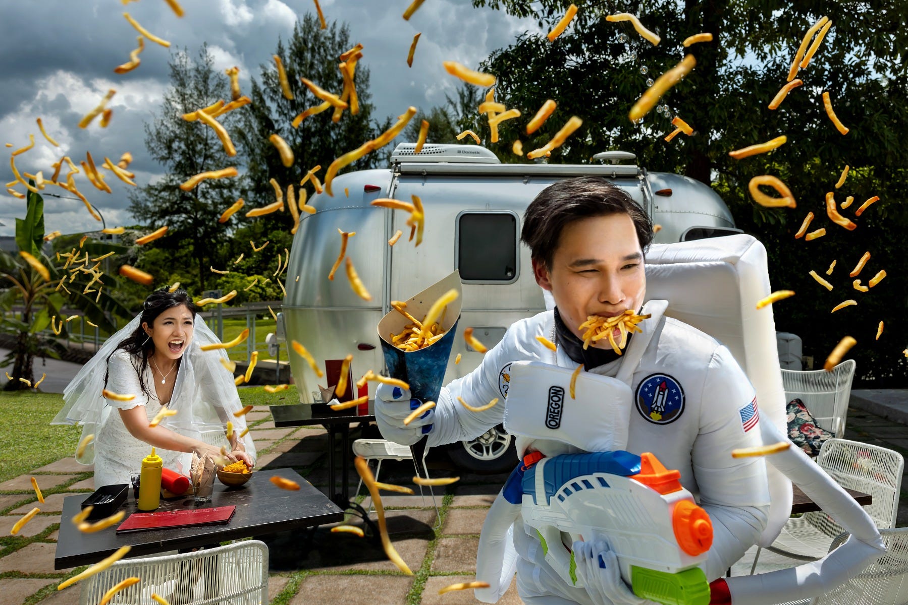 Wedding couple throws French fries in a dramatic pre-wedding photoshoot.]