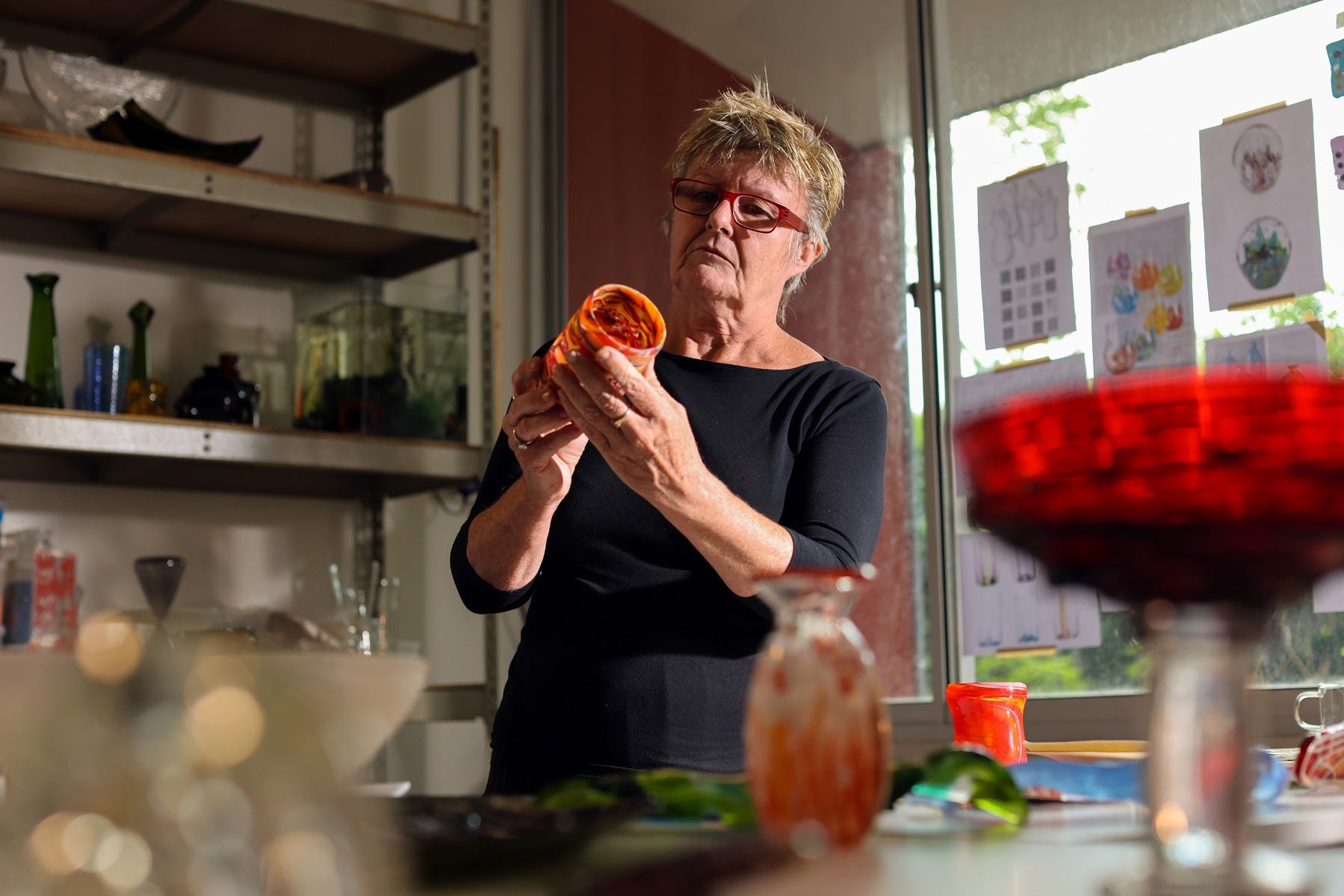 Barbara in her studio studying her recycled glass piece intently